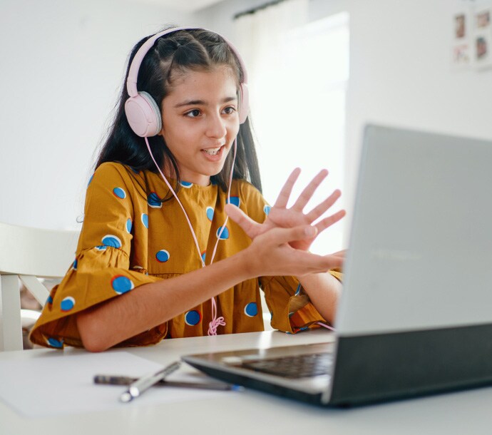 jente som sitter ved en pult og bruker en datamaskin som starter Norton Family.
