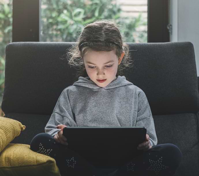jente som sitter på sofaen med en datamaskin som starter Norton Family.