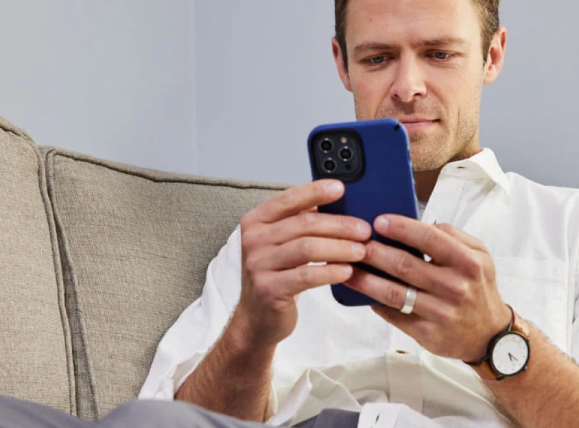 Mann på en sofa som ser på en telefon