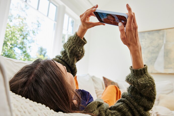 Kvinne som ligger mens hun ser på en mobiltelefon
